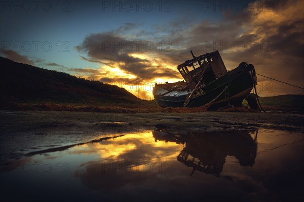 Shipwreck on beach at sunset