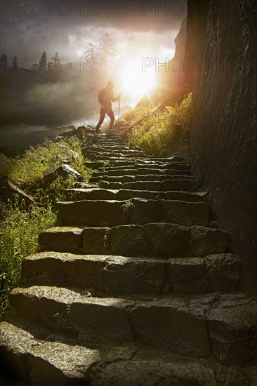 Distant hiker on stone staircase at sunset