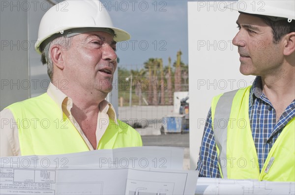 Hispanic construction workers reviewing blueprints