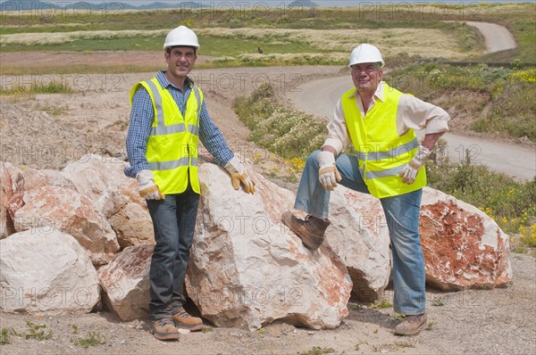 Hispanic construction workers standing near boulders