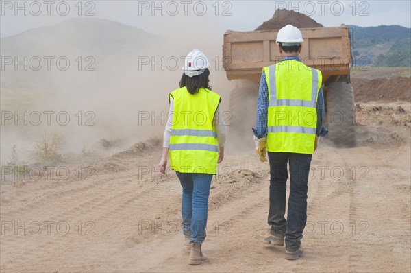 Construction workers walking behind dump truck