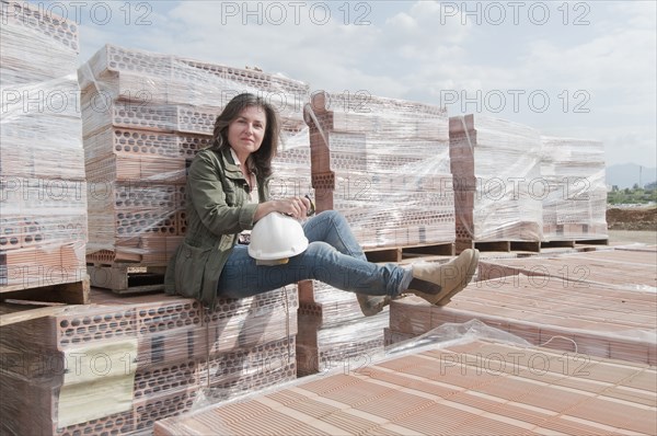 Caucasian construction worker sitting on stack of bricks