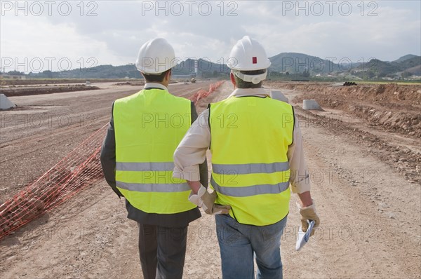 Hispanic businessman and construction worker standing in field