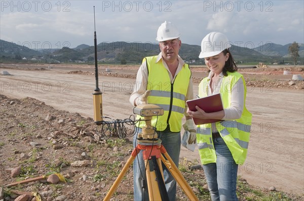 Construction workers examining equipment in field