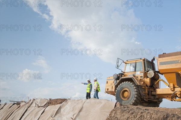 Hispanic construction workers in field with dump truck