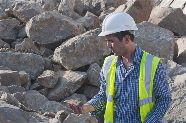 Hispanic construction worker looking at rock