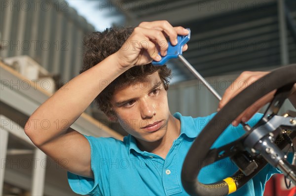 Hispanic teenager working on go-cart