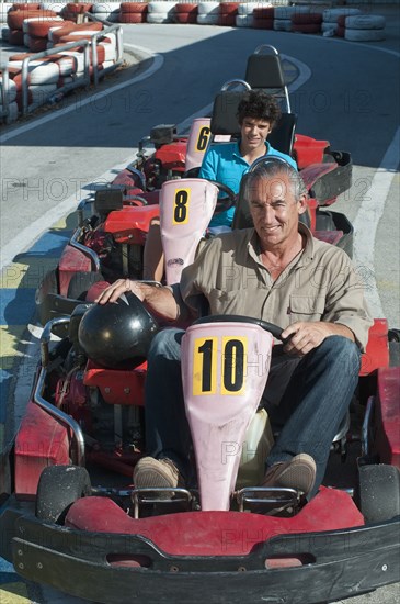 Hispanic grandfather and grandson on go-cart track