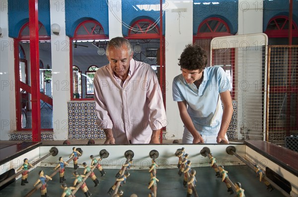 Hispanic grandfather and grandson playing foosball