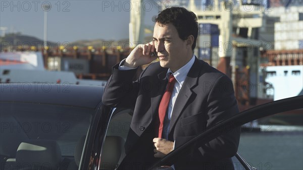 Hispanic businessman talking on cell phone on dock
