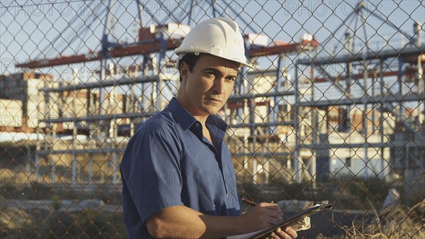 Hispanic man with clipboard on construction site