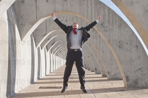 Hispanic businessman jumping in mid-air