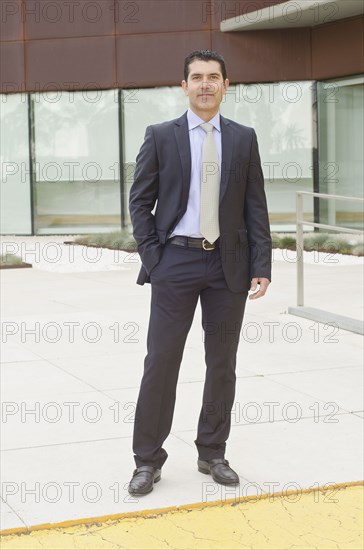 Hispanic businessman standing in office courtyard