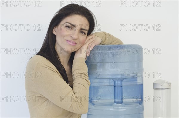 Hispanic businesswoman leaning on water cooler