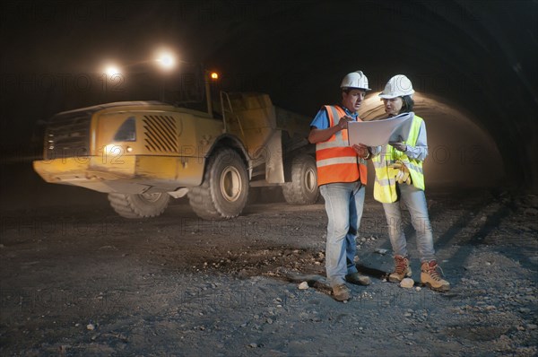 Construction workers looking at blueprint in tunnel