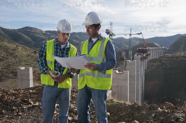 Construction workers looking at blueprint at construction site