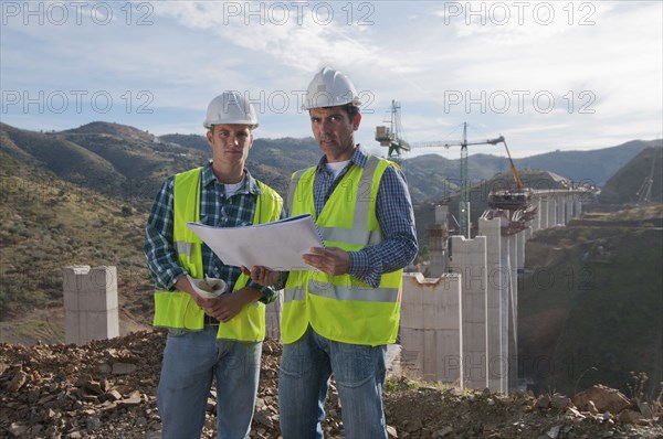 Construction workers looking at blueprint at construction site