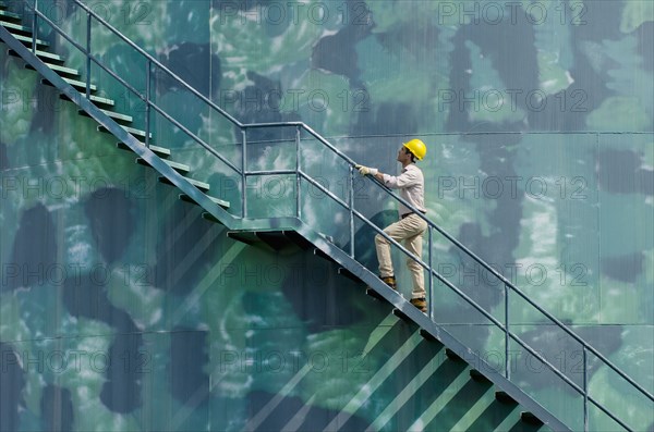 Hispanic worker climbing water tower