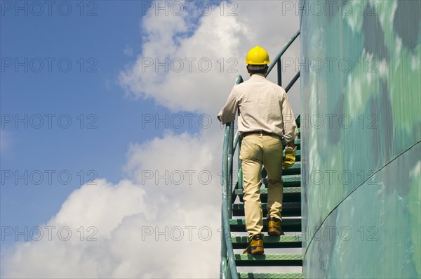 Hispanic worker climbing water tower