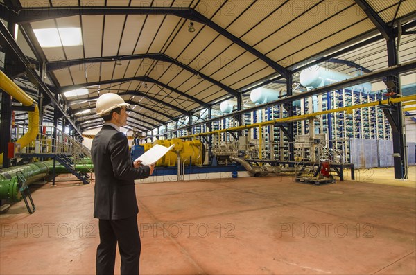 Hispanic businessman checking machinery