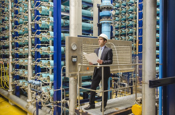 Hispanic businessman checking machinery