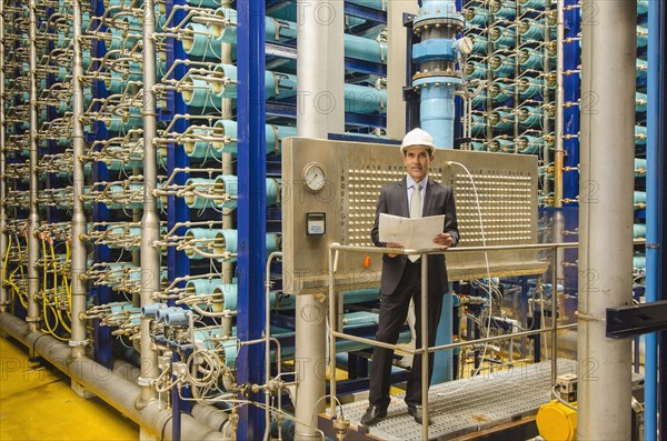 Hispanic businessman checking machinery