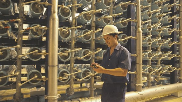 Hispanic worker with cell phone in warehouse