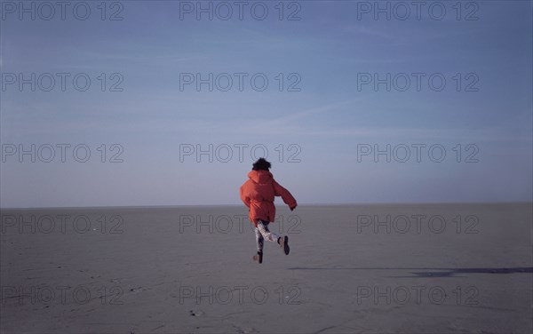 Woman running on sand flats rear view