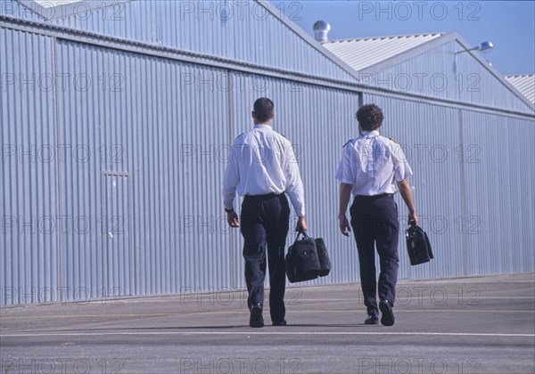 Aircraft pilots walking near hangars rear view