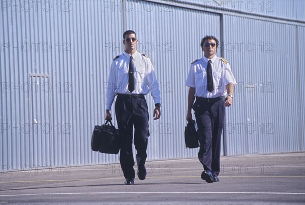 Two pilots walking in front of hangars