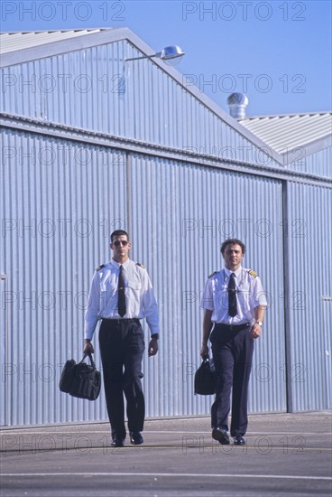 Two pilots walking in front of hangars