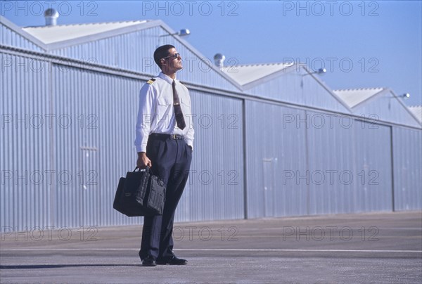 Pilot on tarmac looking at sky