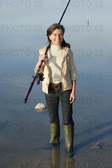 Woman with fishing rod standing in lake portrait elevated view