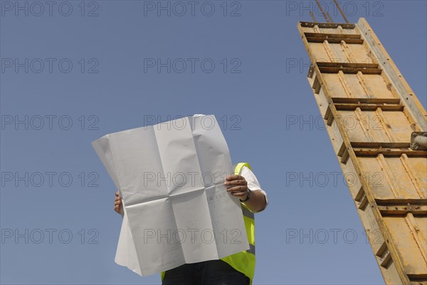 Engineer looking at plan on construction site low angle view