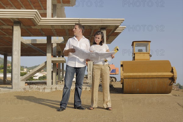 Couple looking at blueprints at construction site