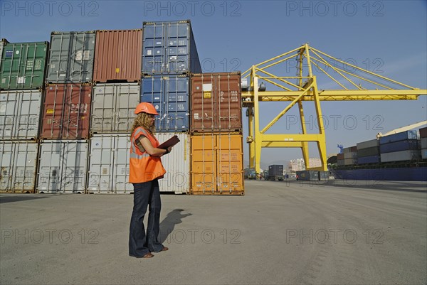 Female worker with clipboard in cargo container terminal