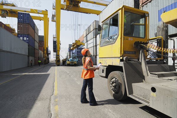 Female worker with clipboard in cargo container terminal