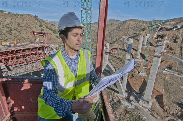 engineer with plans at bridge construction site