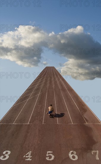 Lone sprinter at starting position on track in clouds (Digital Composite)