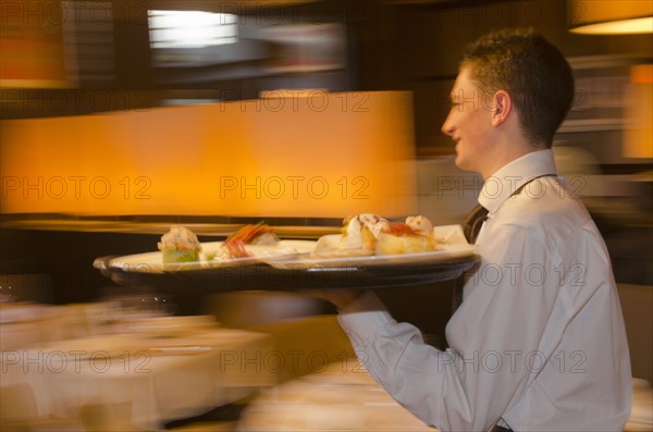 Waiter carrying tray with dishes through resturant