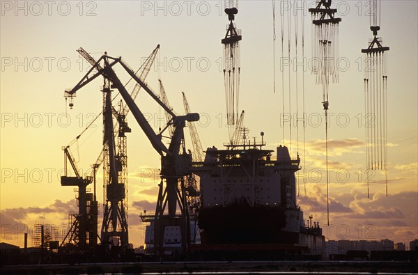 Cranes and a Tanker Moored at a Harbour at Sunset