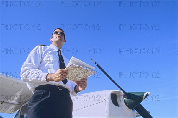 Low Angle Shot of a Pilot Holding a Map and Standing by a Private Propeller Plane