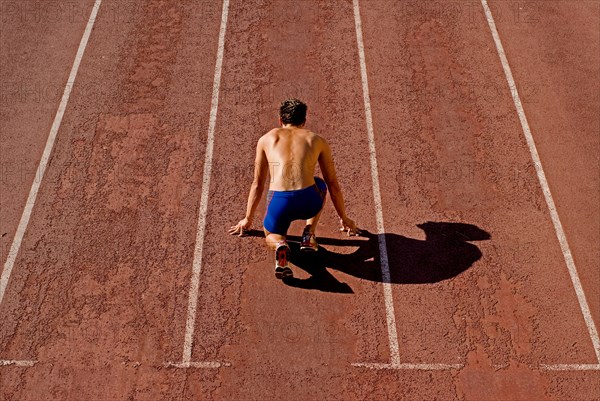 Runner on starting position of running track rear view