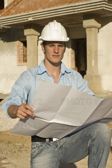 Young architect with plan on construction site