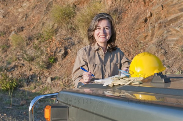 female engineer using car hood as desk