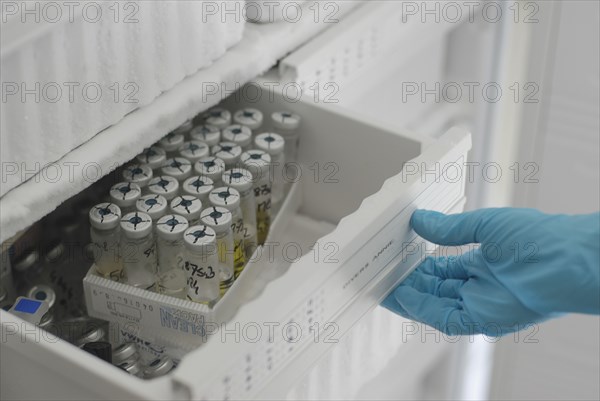 Lab technician opening freezer full of test tubes in laboratory close-up of hand