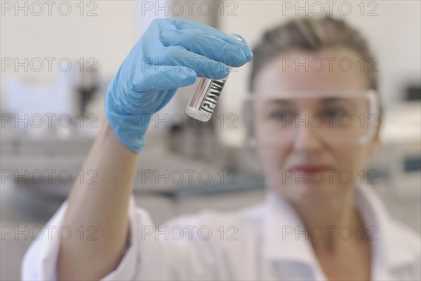 Lab technician looking at sample bottle in laboratory focus on hand