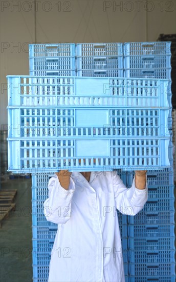 Woman holding crates in front of face