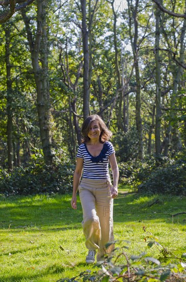 woman walking across clearing in forest