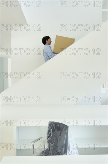 Young man carrying box upstairs side view